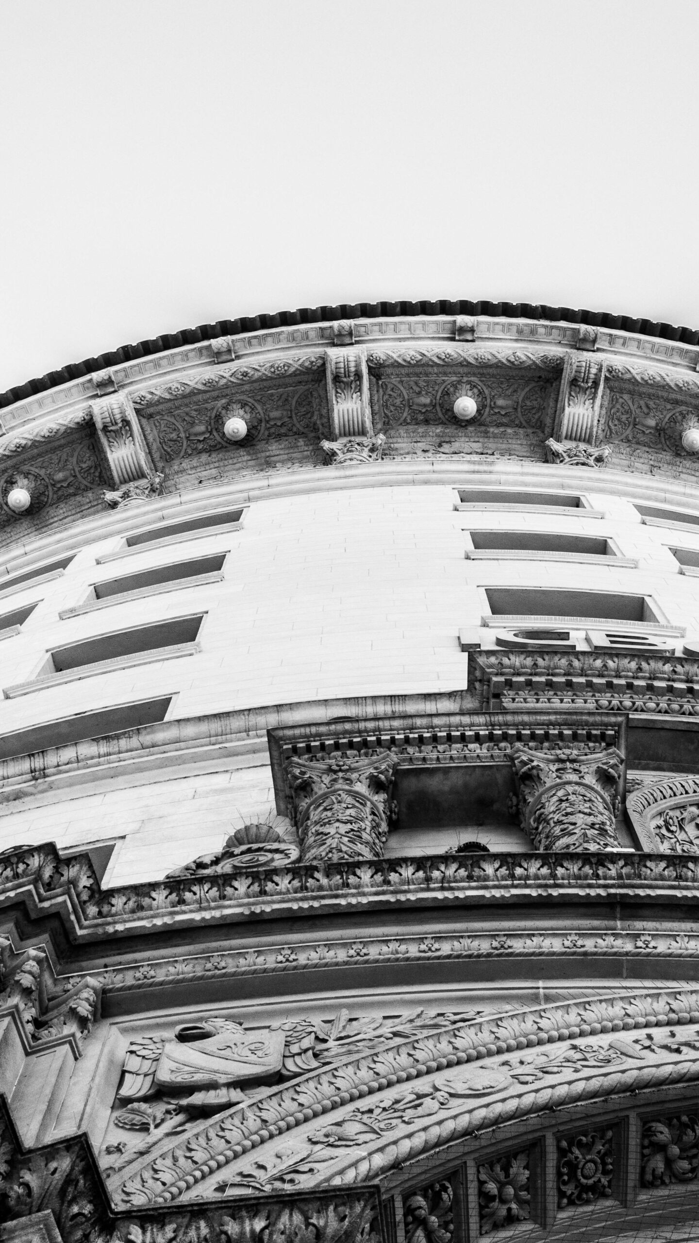 Black and white image capturing the intricate architectural details of a historic building facade from a low angle.